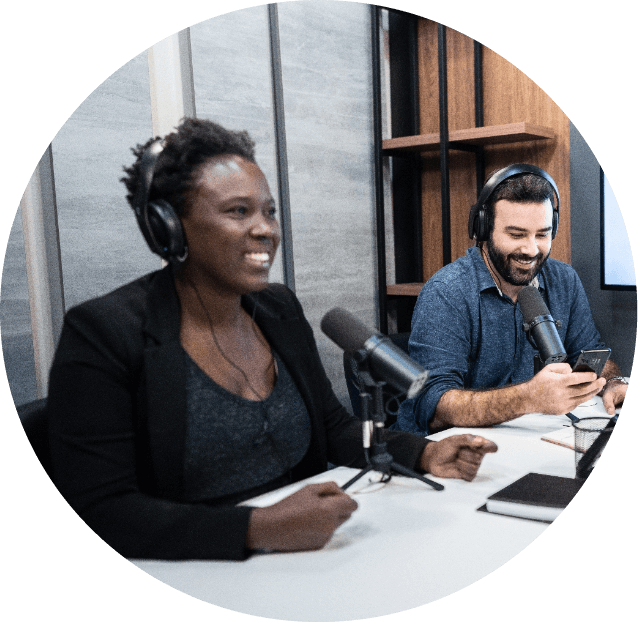 black woman and white man in front of microphones recording a podcast